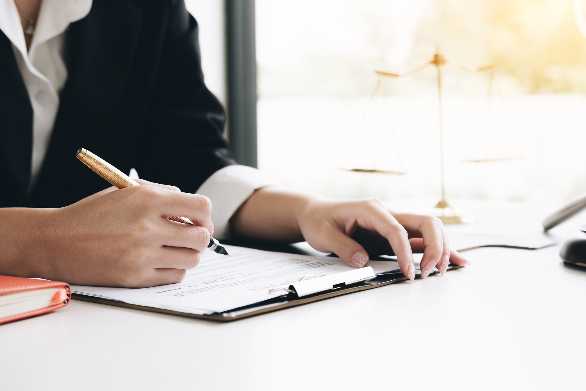 Business woman and lawyers discussing contract papers with brass scale on wooden desk in office. Law