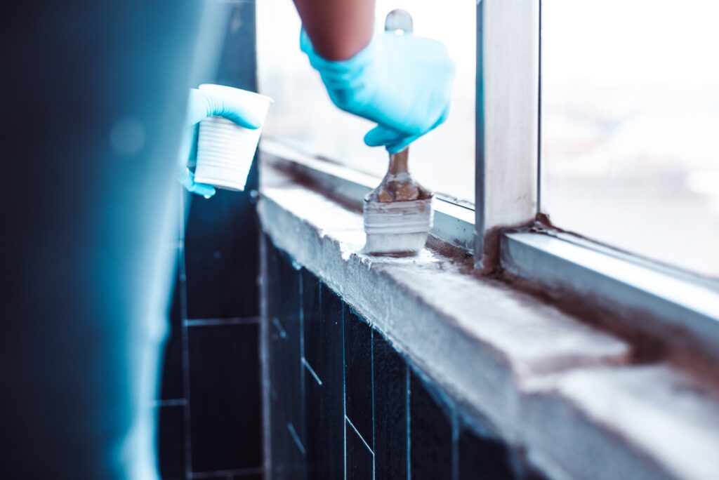 Hands in gloves painting a white wall