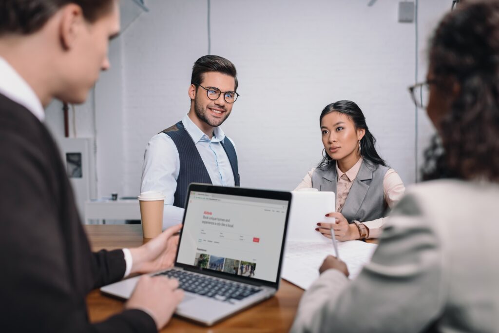 multiethnic business team with documents and laptop with airbnb website