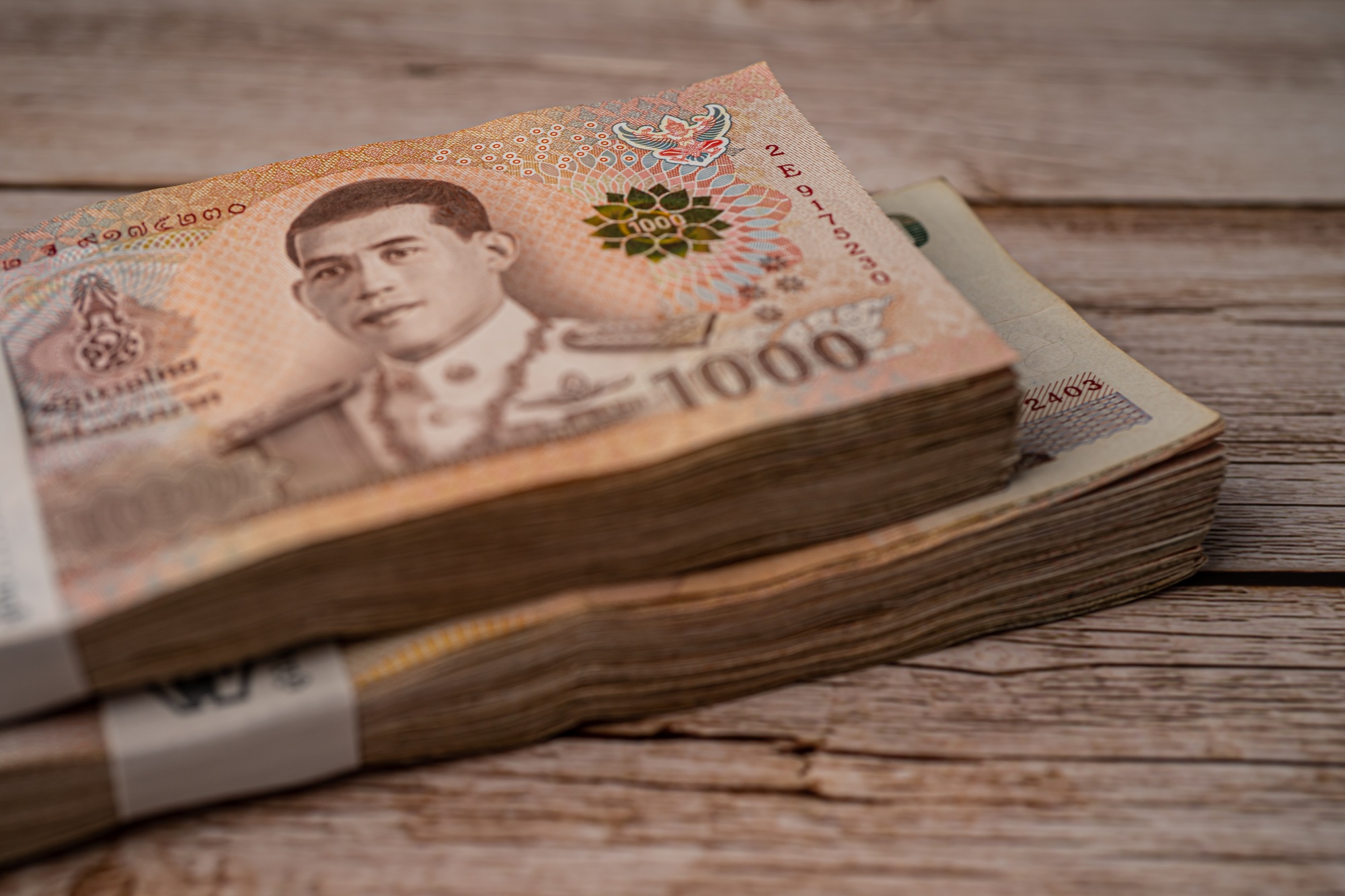 Stack of Thai baht banknotes on wooden background, business saving finance investment concept.