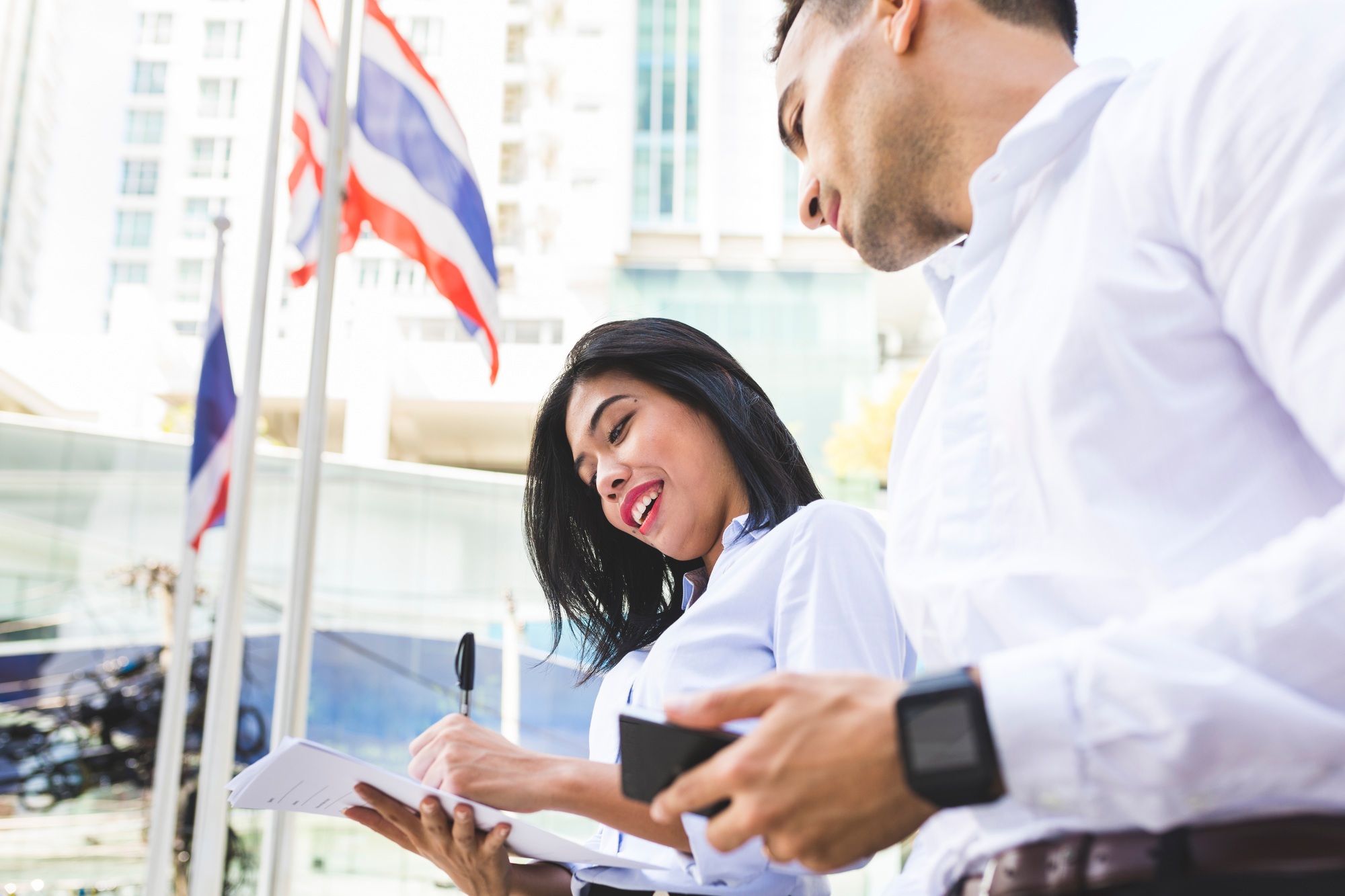 Thailand, Bangkok, businessman and businesswoman in the city with documents, cell phone and smartwat