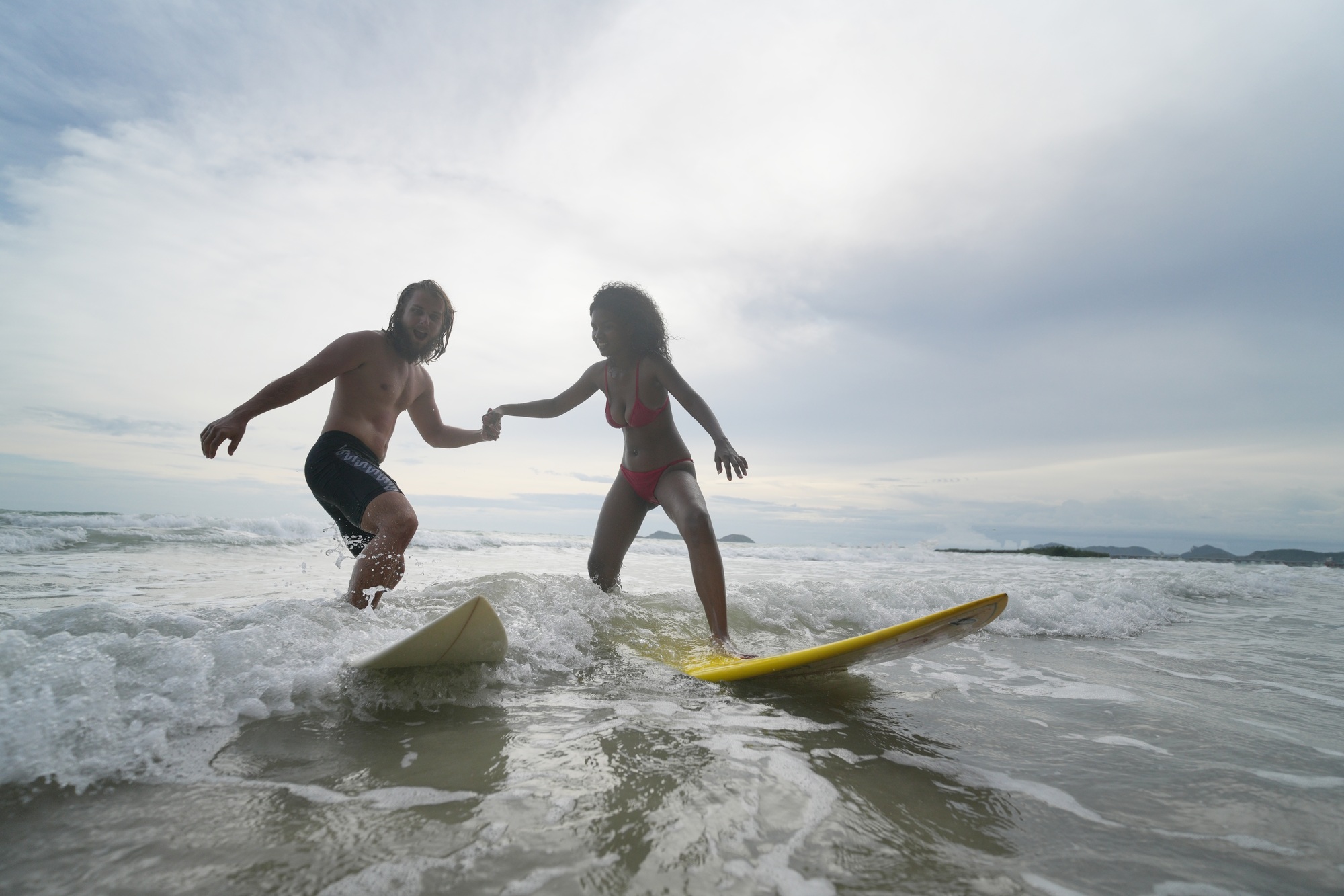 Happy couple surfing together on beach with surfing board in Pattaya, Thailand.