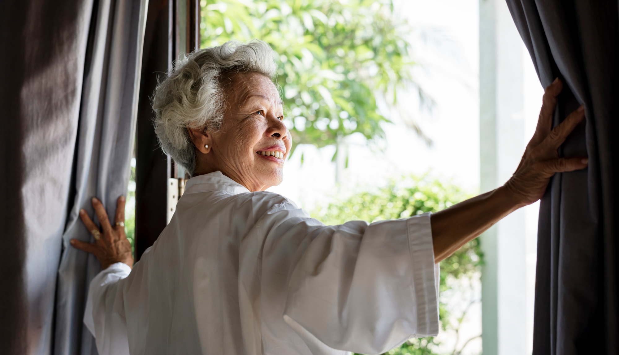 Senior woman opening the curtains