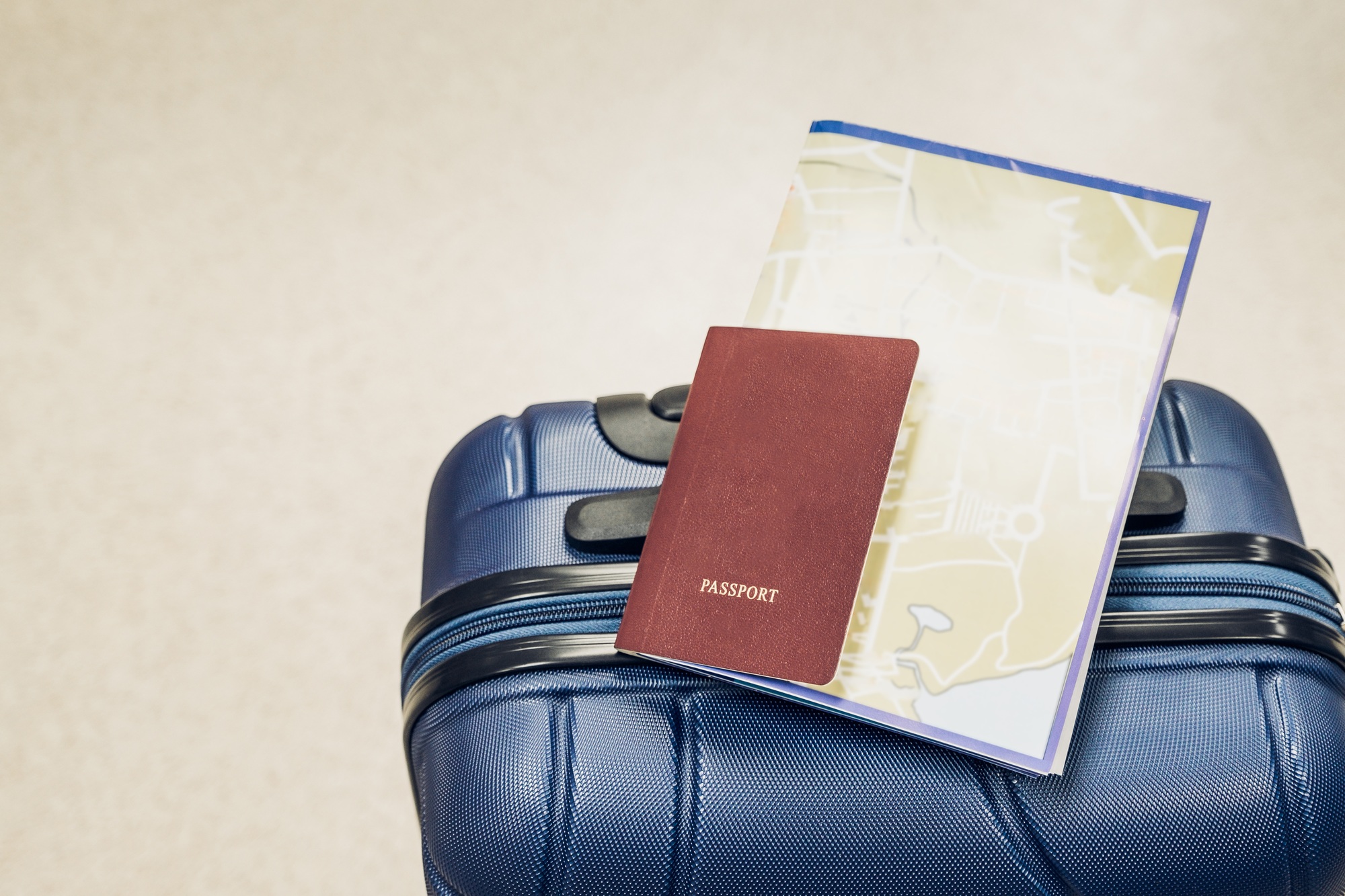 Close up passport and map lay on blue suitcase at airport