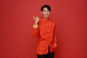 Happy Chinese new year. Asian man wearing red traditional costume and hands pointing finger up