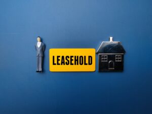 Mninature people and toys house with the word LEASEHOLD. Business concept