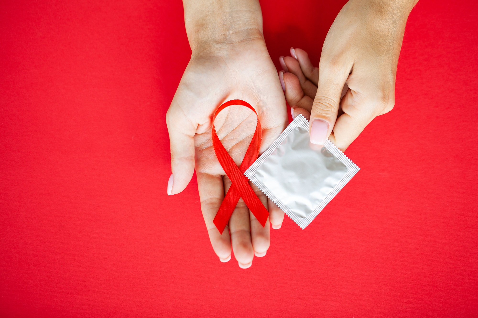 Close Up woman hand holding red ribbon HIV, world AIDS day awareness ribbon.