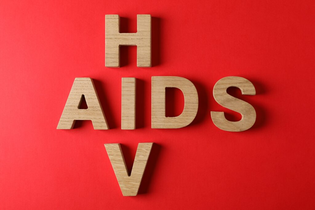 Words AIDS and HIV on red background, space for text