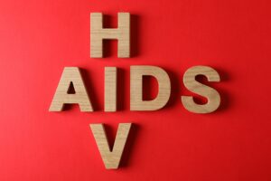 Words AIDS and HIV on red background, space for text